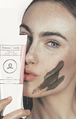 Girls with creamy face scrub on face and holding tube