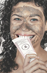 Girl with creamy face scrub on face and biting tube