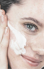 Girls with creamy face scrub on face and holding tube