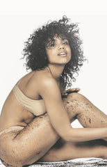 Girl sitting down rubbing coffee scrub on her legs